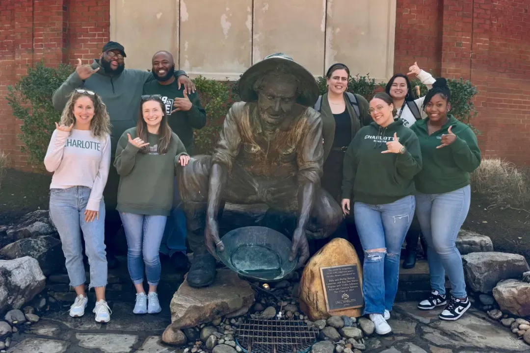 UNC Charlotte staff members standing near the Norm statue